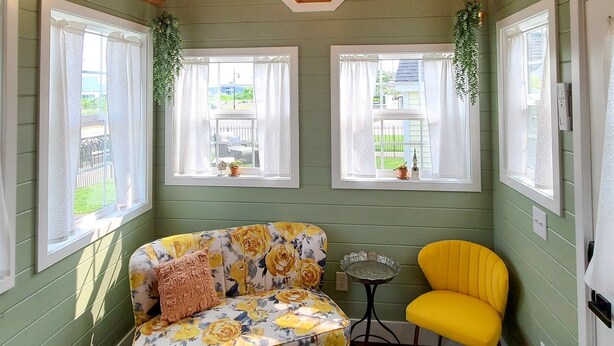 Una habitación acogedora con techo de madera, un sofá floral, un sillón amarillo y una mesita.