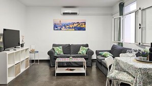 Un salon moderne avec un canapé, une table basse, un téléviseur et un tableau accroché au mur.