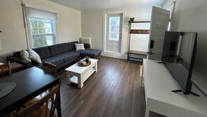 Una sala de estar moderna con un sofá seccional, una mesa de centro, una mesa de comedor y un televisor de pantalla plana.