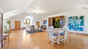 A spacious loft with high ceilings, a dining area with white chairs, and a large abstract painting on the wall. - Historic Manor House Private Guest Suite Evanston (Evanston)