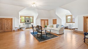 A spacious loft with high ceilings, wooden floors, and a cozy seating area with a white sofa and chairs. - Historic Manor House Private Guest Suite Evanston (Evanston)