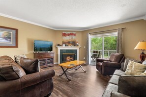 A living room with a fireplace, leather sofas, a coffee table, and a television. - 2BD 2BA|Indoor Pool and Hot Tub| Handicap Accessible Bath| Sleeps 6 (Pigeon Forge)