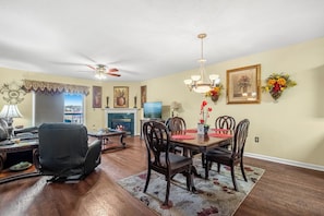 A dining area with a wooden table, chairs, and a chandelier. There is a television on a stand and a fireplace in the background. - Two bedroom, two bathroom condo located in near Dollywood (Pigeon Forge)