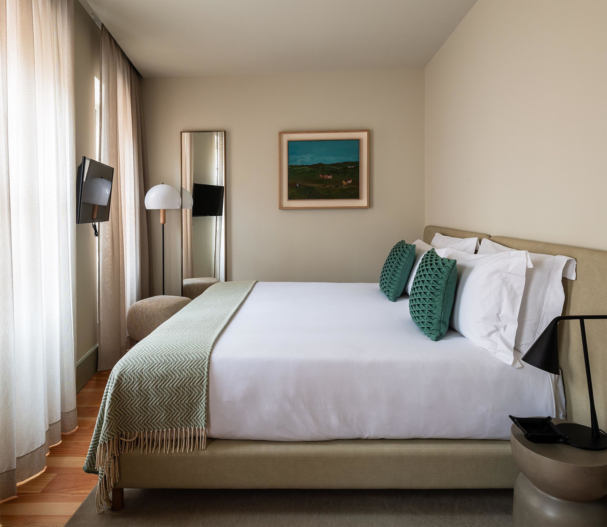 Quarto de hotel bem arrumado, com cama, televisão de tela plana, um quadro e abajur.