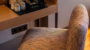 A cozy room with a wooden desk, a coffee machine, and a woven chair.