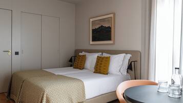 Quarto com cama, mesa de cabeceira, cadeira, mesinha e um quadro na parede.