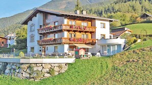 Hotel de vários andares com varandas decoradas com flores, com montanhas ao fundo.