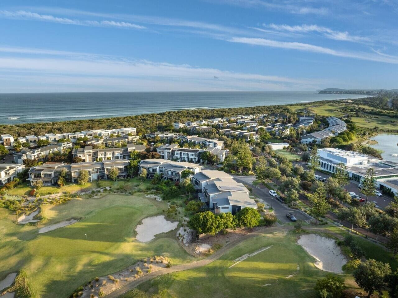 Une zone résidentielle située sur la côte, avec des maisons, un terrain de golf et une étendue d’eau.
