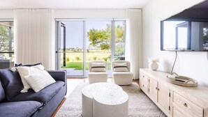 Un salon moderne avec un canapé, des fauteuils, une table basse et un téléviseur.