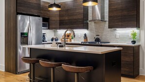 Una cocina moderna con muebles de madera oscura, electrodomésticos de acero inoxidable e iluminación colgante.