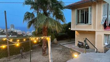 Une maison avec un palmier, un scooter et des guirlandes lumineuses.