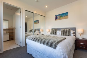 A bedroom with a large bed, a wardrobe, a mirror, and a painting on the wall.