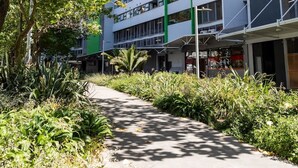 A multi-story building with a modern architectural design, surrounded by lush greenery and a paved walkway. - Stunning Views Central Apt (Auckland)