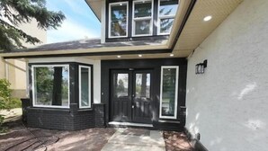 A modern two-story house with large windows, a dark front door, and a concrete walkway leading to the entrance.