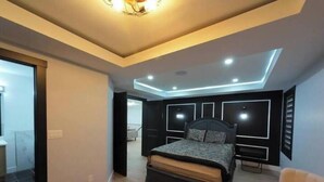A modern bedroom with a large bed, built-in headboard, and recessed ceiling lighting.
