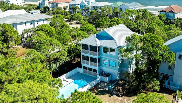 A coastal residential area with multiple houses, a swimming pool, and a view of the ocean.