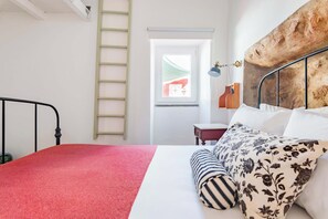A bedroom with a bed, a ladder, a window, and a headboard.
