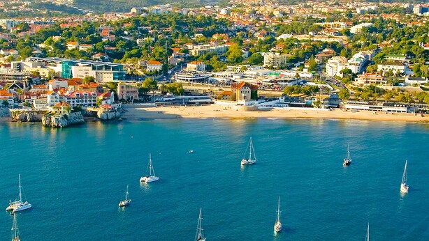 A coastal town with a marina, sandy beach, and buildings with red roofs. - Casalinho de Bicesse (Cascais)