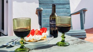 Two wine glasses, a bottle, and a dessert on a table outdoors. - Casalinho de Bicesse (Cascais)