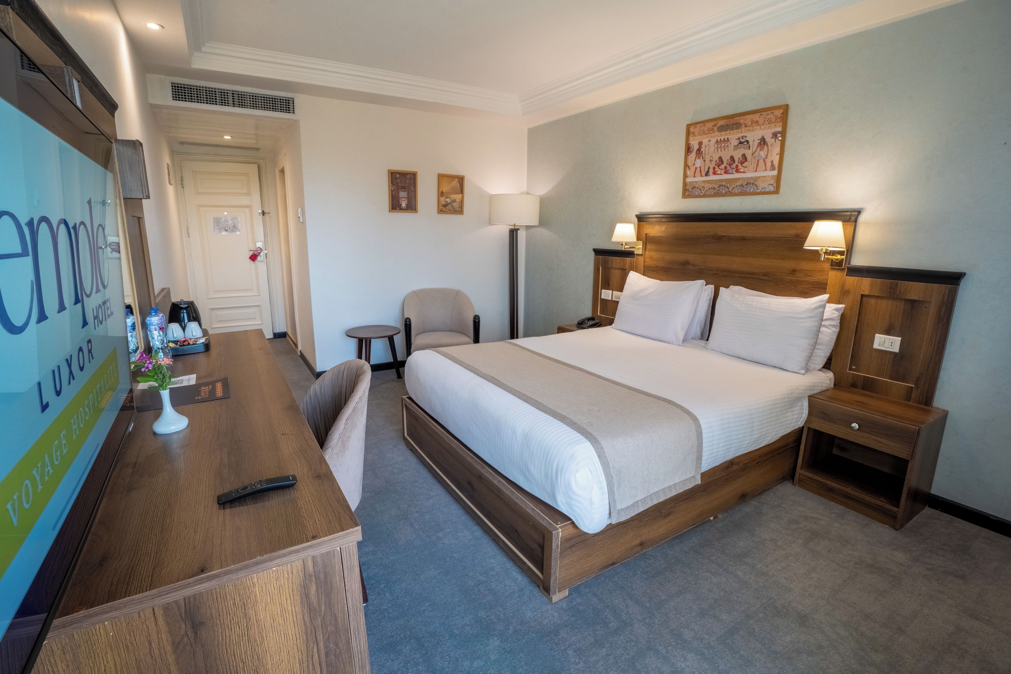 A hotel room with a bed, bedside tables, a desk, and a chair.