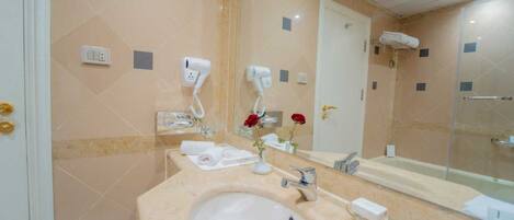 Un baño con lavamanos, espejo y dos secadores de pelo en la pared.