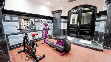 Une salle de sport équipée de matériel d’exercice, avec un miroir et une porte noire.