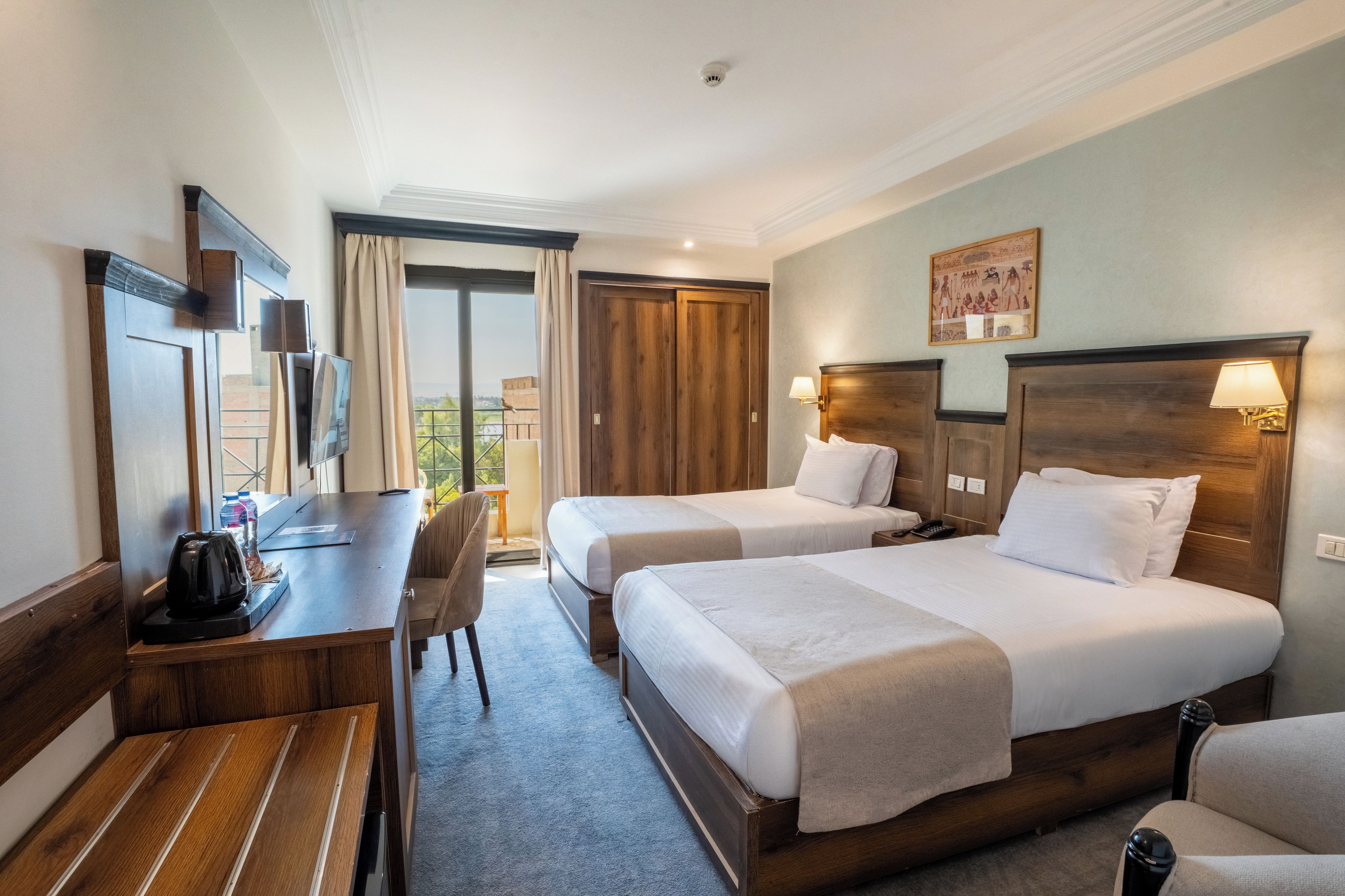 Une chambre d’hôtel avec deux lits, un bureau, une chaise et un balcon avec vue.