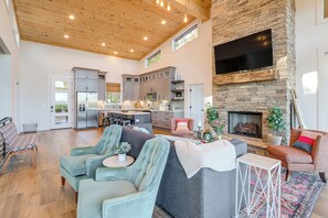 A spacious living area with a stone fireplace, modern kitchen, and comfortable seating.