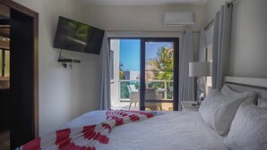 Ein Hotelzimmer mit Bett, Wandfernseher, Klimaanlage und Balkon mit Sitzmöbeln.