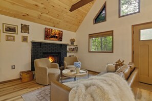 Ein gemütliches Wohnzimmer mit Kamin, Holzbalkendecke und einer Couch.