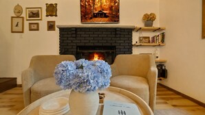 A room with two sofas, a fireplace, framed pictures on the wall, and a welcome sign.