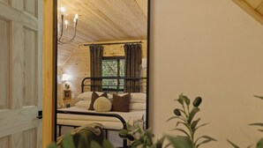A bedroom with a bed, a nightstand, a lamp, and a window with curtains.