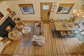 Amplia sala de estar con chimenea, sofá de cuero y comedor con mesa y sillas de madera.