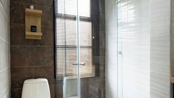 Un baño con ducha envuelta en vidrio, inodoro y tocador con espejo.