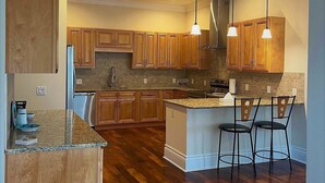 Cucina con mobili in legno, piano di lavoro in granito e isola centrale con sgabelli da bar.