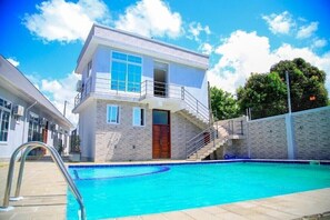 A two-story building with a swimming pool in front. - Mega Lodge
 (Dar es Salam)