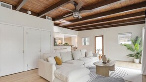 A spacious living area with a large sectional sofa, a round coffee table, and a ceiling fan.