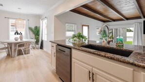 A modern kitchen with a granite countertop, stainless steel dishwasher, and white cabinetry.