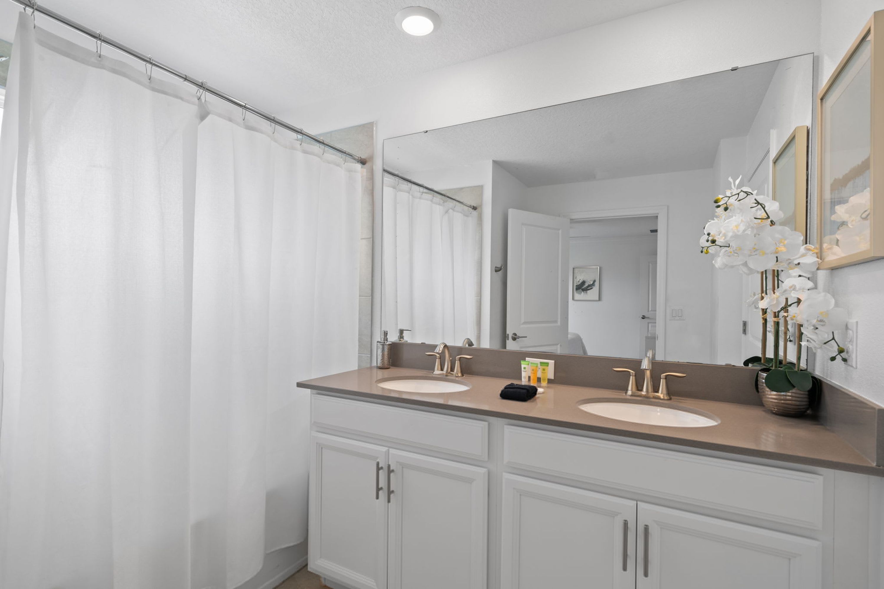 A bathroom with two sinks, a large mirror, and a shower curtain.