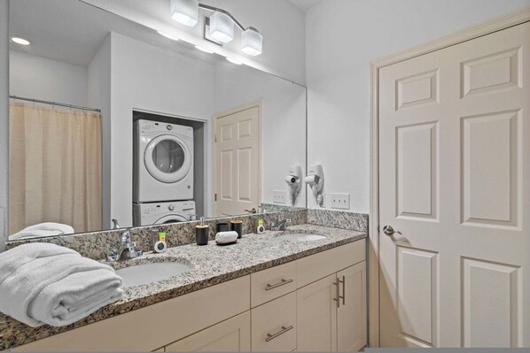 Une salle de bain équipée d’un lavabo, d’un miroir et d’un lave-linge.