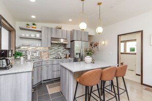 Eine moderne Küche mit Granit-Arbeitsplatten, Edelstahlgeräten und einer zentralen Kochinsel mit Barhocker.