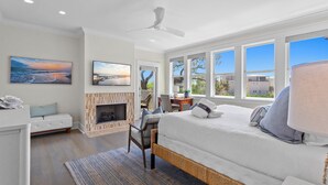 A modern bedroom with a large bed, a fireplace, and a view of the outdoors. - Just Shellin' - Santa Rosa Beach, Walk to Shops + Dining, Walk to Beach! (Santa Rosa Beach)