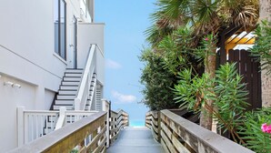 A wooden boardwalk leading to a staircase and a building with a white facade. - Just Shellin' - Santa Rosa Beach, Walk to Shops + Dining, Walk to Beach! (Santa Rosa Beach)