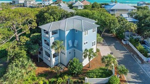 A multi-story building with balconies, surrounded by lush greenery and a view of the ocean. - Just Shellin' - Santa Rosa Beach, Walk to Shops + Dining, Walk to Beach! (Santa Rosa Beach)