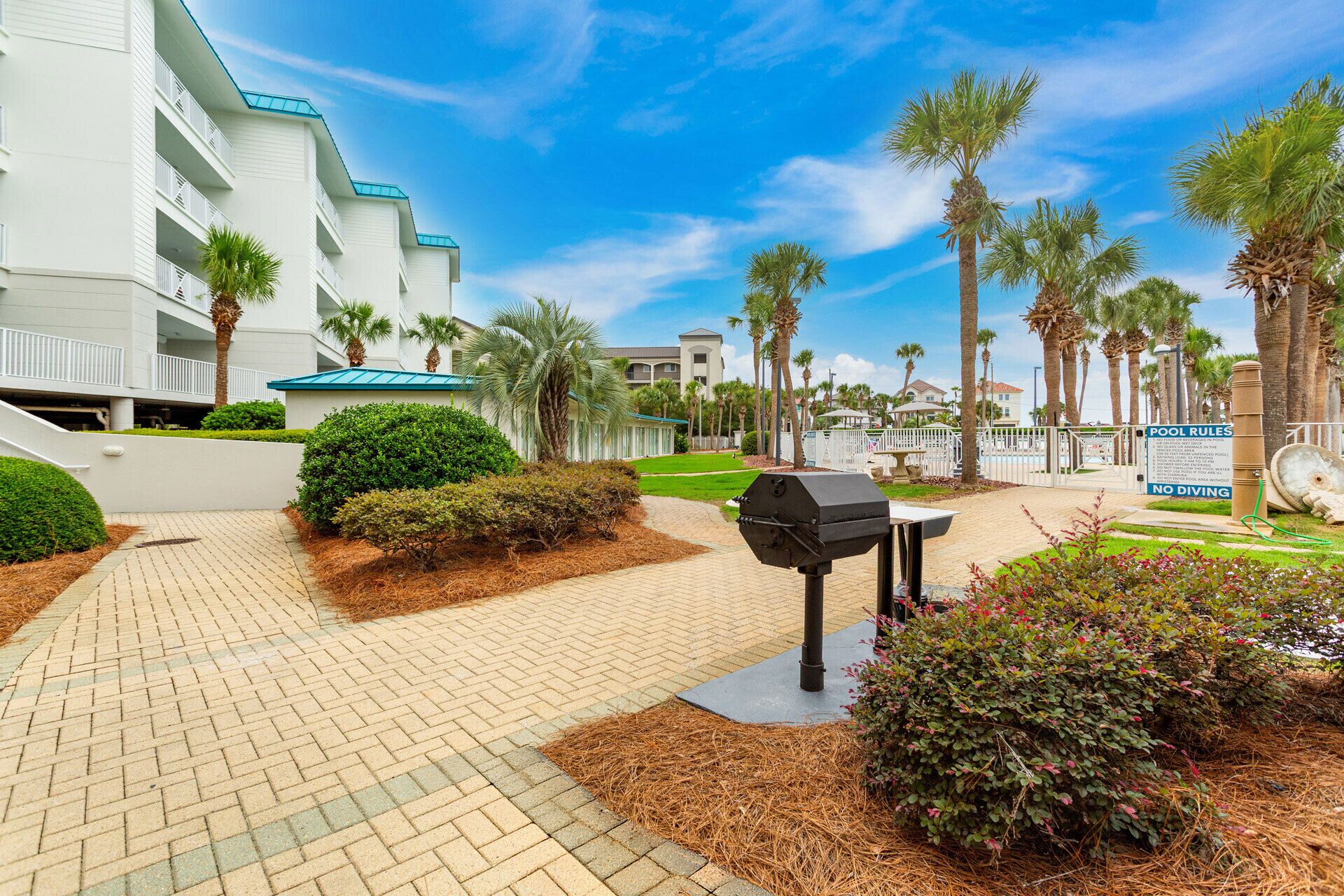 A pathway leading to a pool area with a grill and a sign indicating pool rules.
