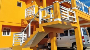 Un edificio a due piani con facciata gialla e ringhiere bianche al livello superiore.