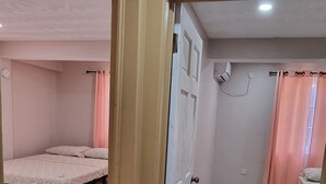 Una stanza con un letto, un tavolino e una porta che dà su un'altra stanza.
