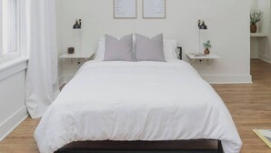 A neatly arranged bedroom with a large bed, two bedside tables, and two framed motivational quotes on the wall. - Room 2-3 (Tulsa)