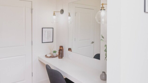 Un baño minimalista con un tocador blanco, un espejo y una sola silla.