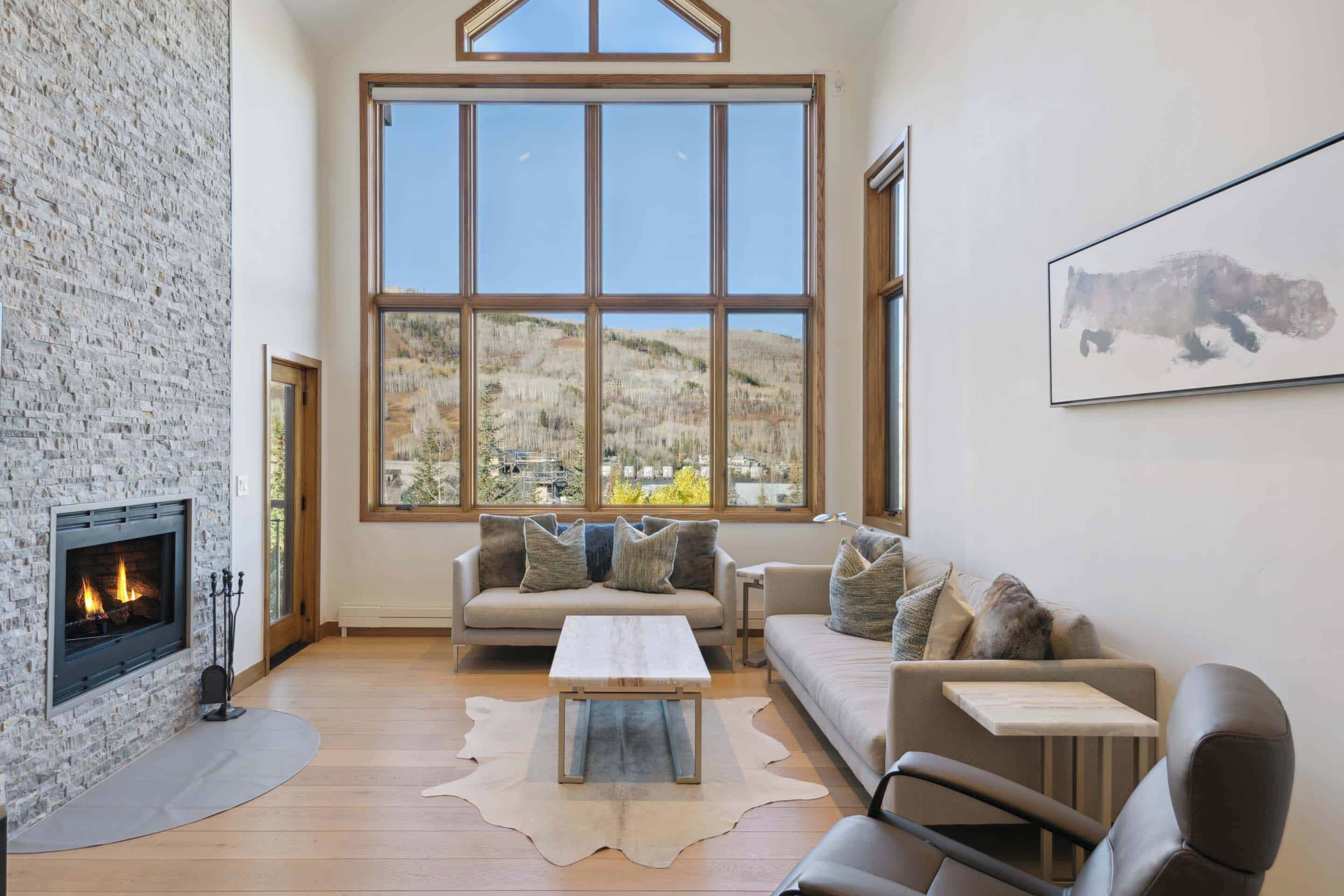 A spacious living room with a fireplace, large windows, and a cozy seating area.
